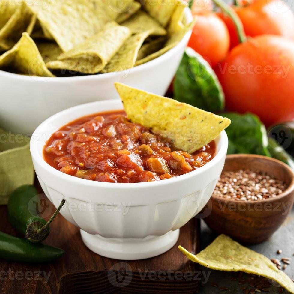 Red tomato spicy salsa with chips photo