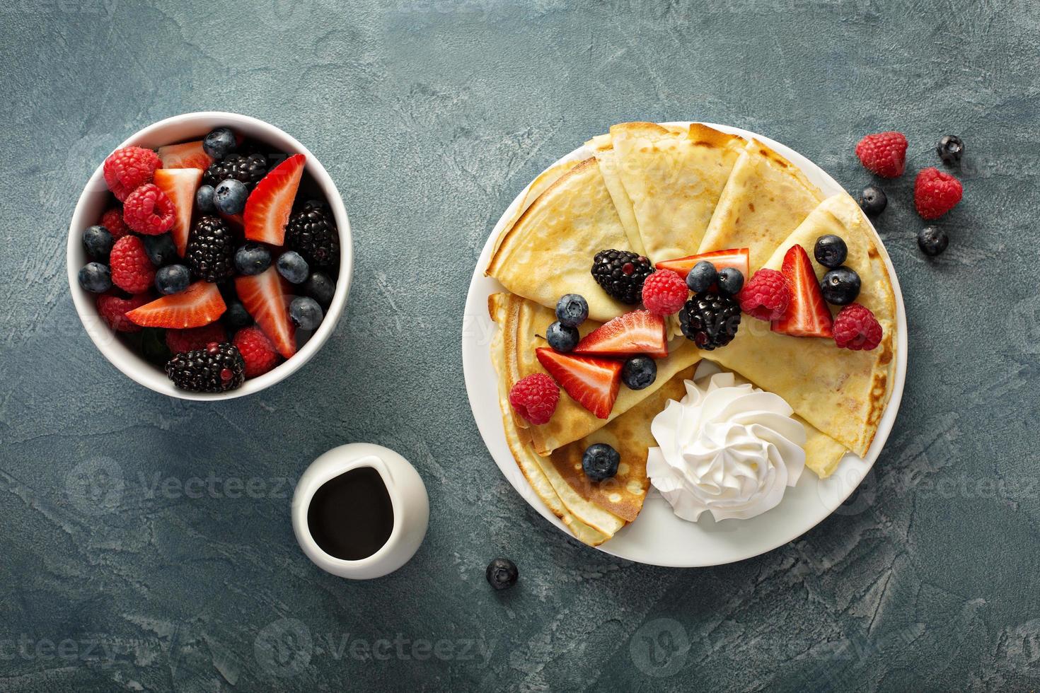 Thin crepes with whipped cream and berries photo