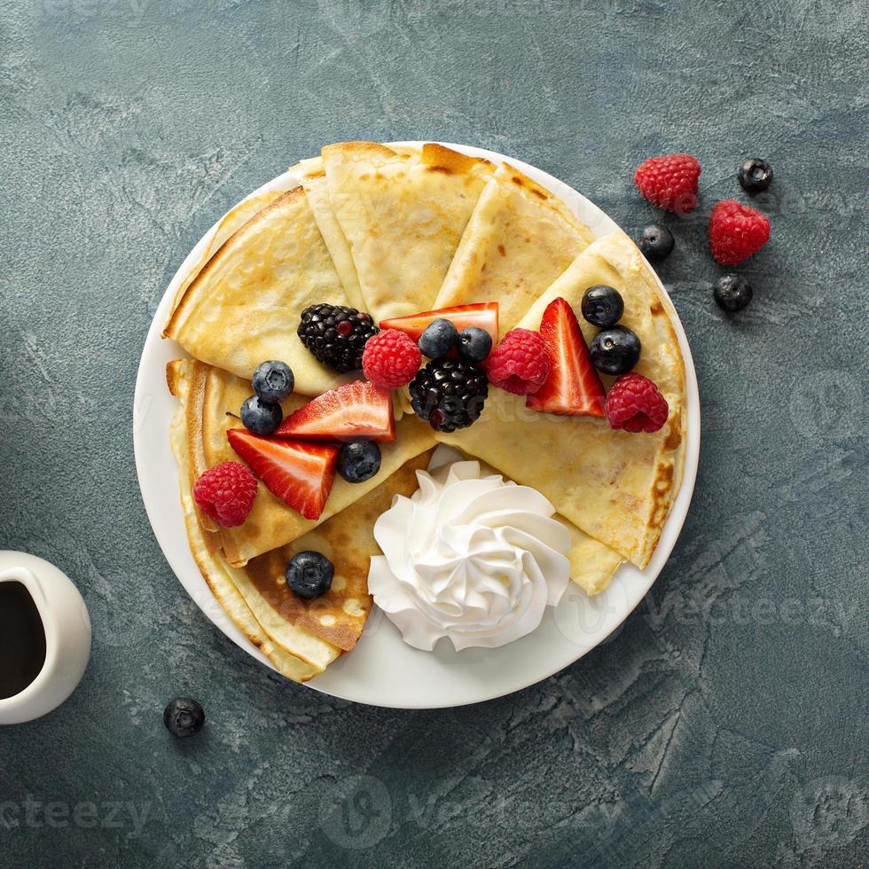 Thin crepes with whipped cream and berries photo