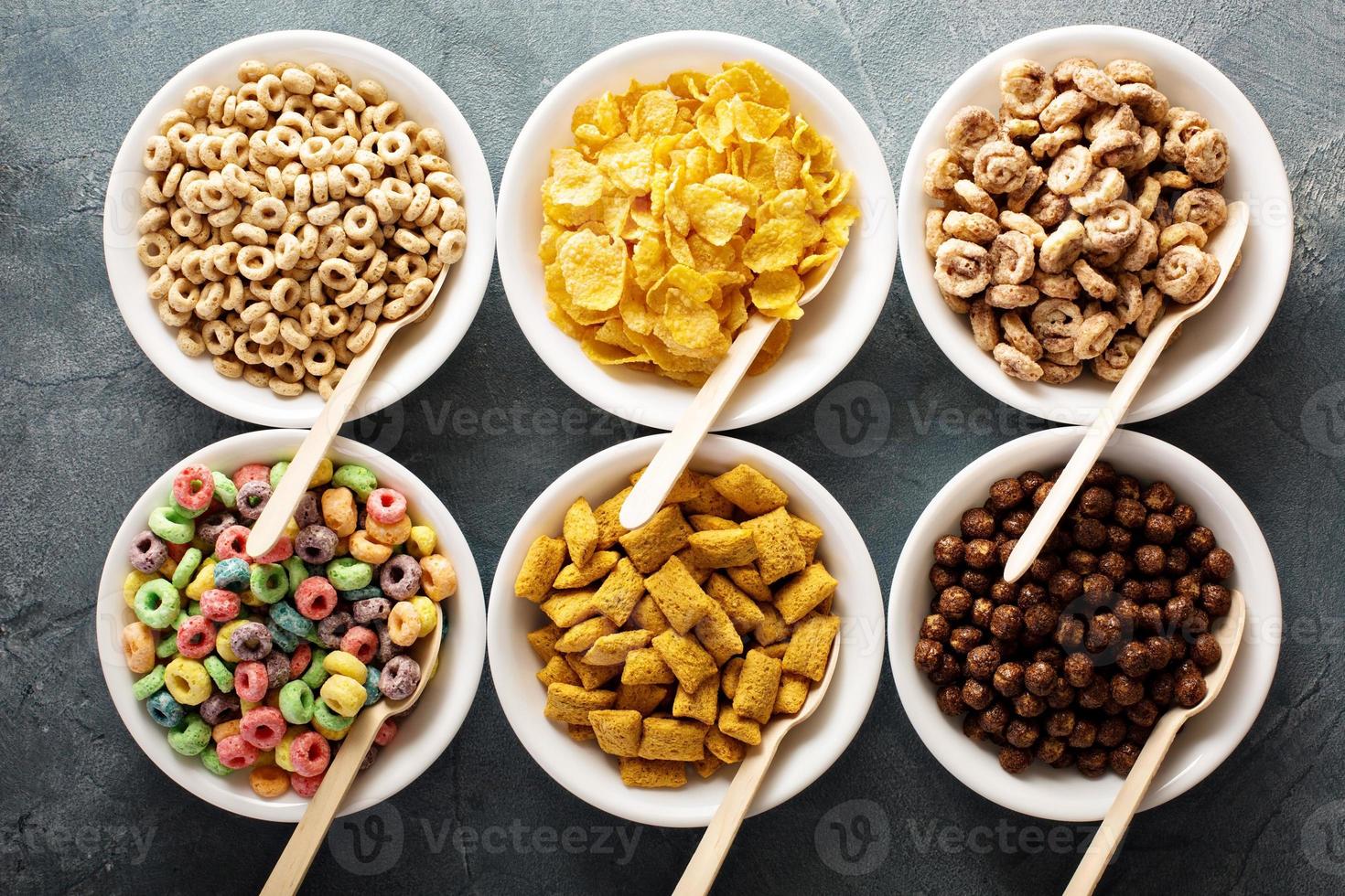 Variety of cold cereals in white bowls with spoons photo