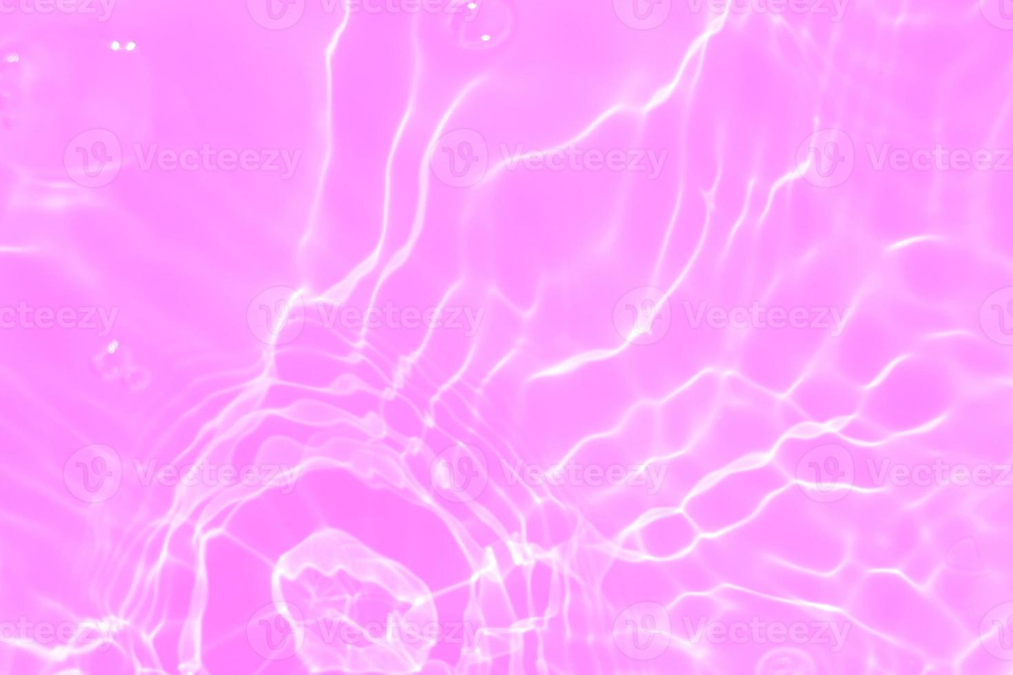 Defocus blurred transparent purple colored clear calm water surface texture with splashes and bubbles. Trendy abstract nature background. Water waves in sunlight with copy space. Pink water drop shine photo