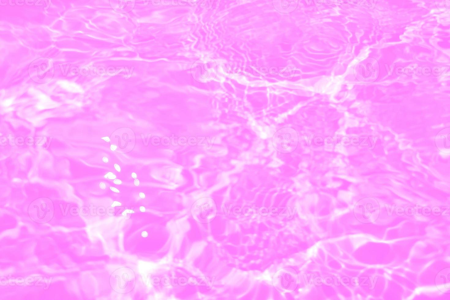 Defocus blurred transparent purple colored clear calm water surface texture with splashes and bubbles. Trendy abstract nature background. Water waves in sunlight with copy space. Pink water drop shine photo
