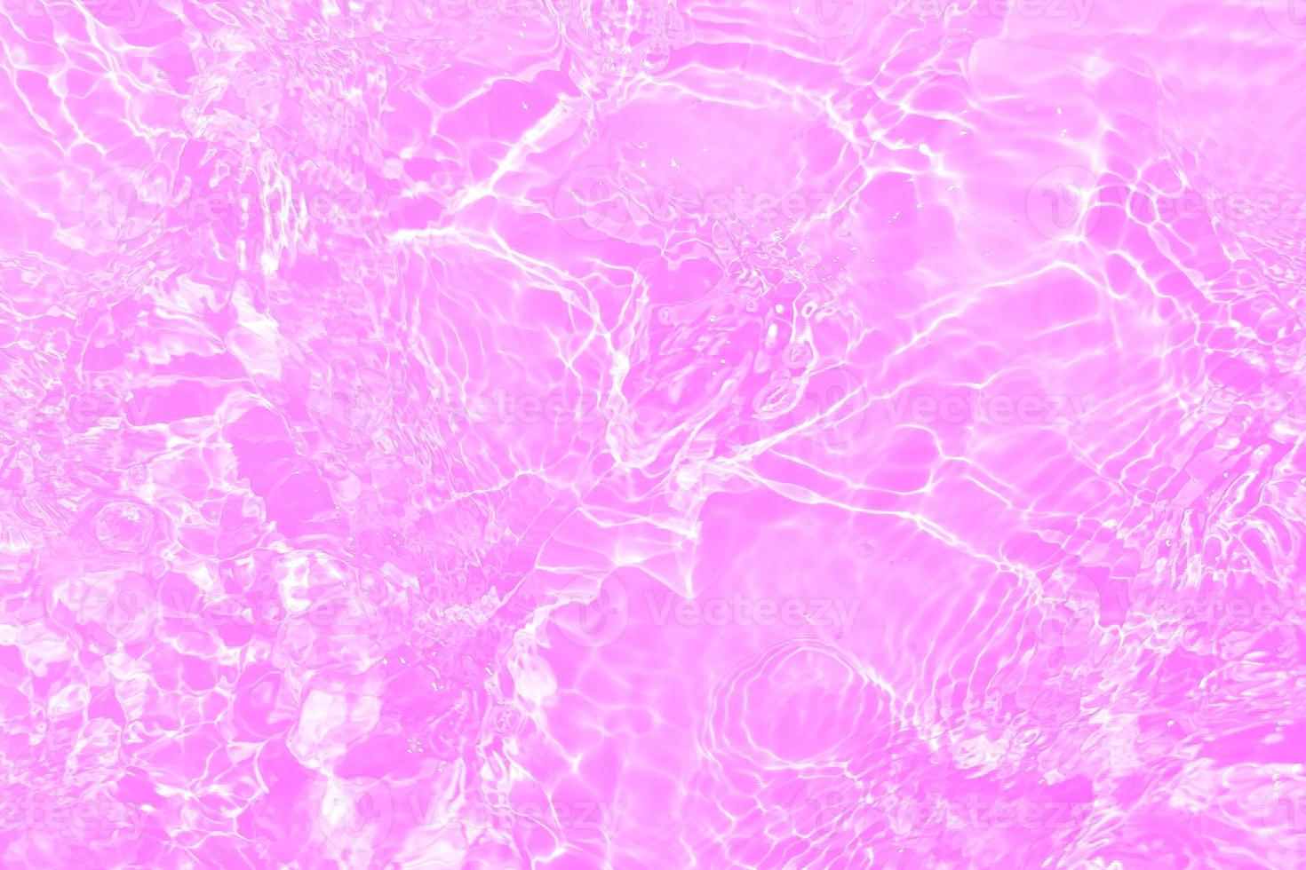 Defocus blurred transparent purple colored clear calm water surface texture with splashes and bubbles. Trendy abstract nature background. Water waves in sunlight with copy space. Pink water drop shine photo