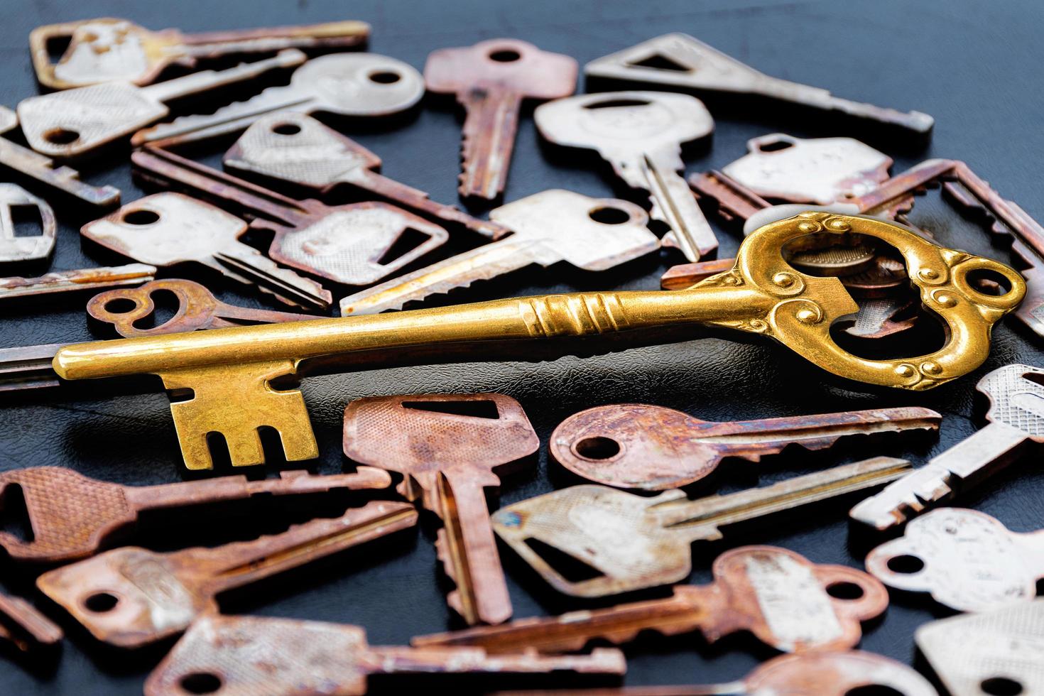 Golden master key in the center of the image. with pattern many keys on black floor photo