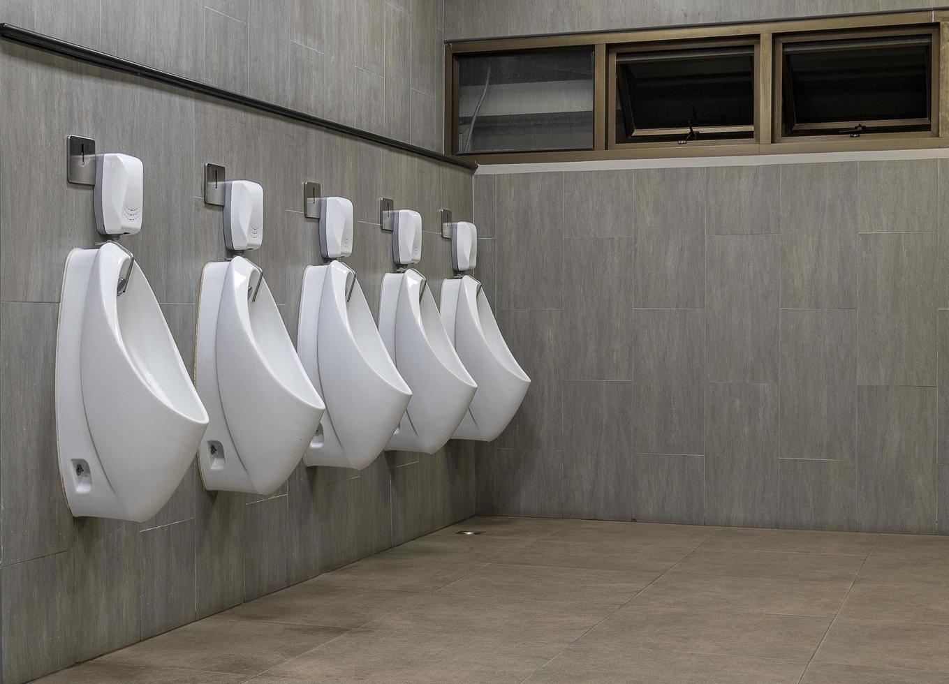 baño de hombres con urinarios de porcelana blanca en línea foto