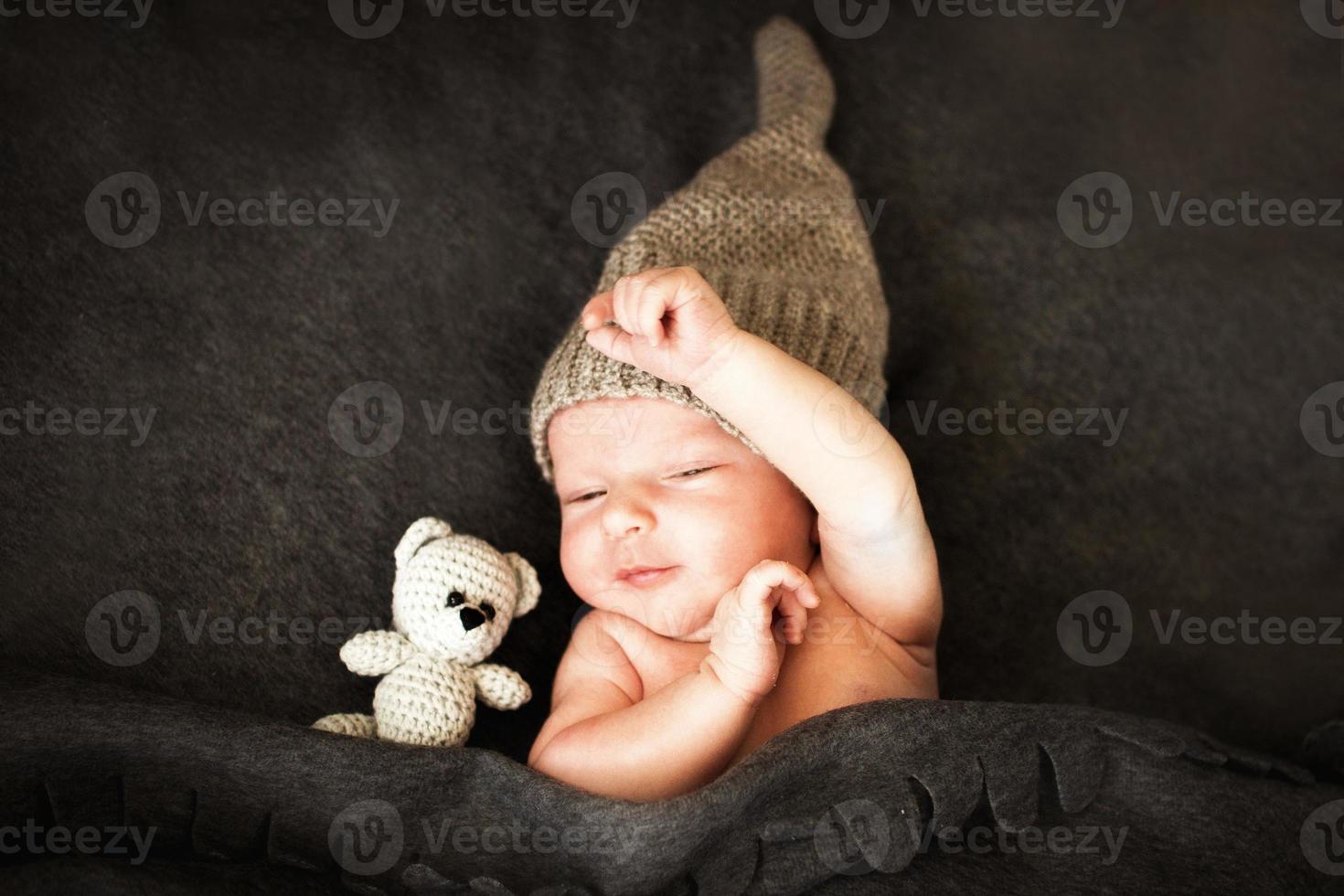newborn baby sleeping with a toy next to the knitted teddy bear