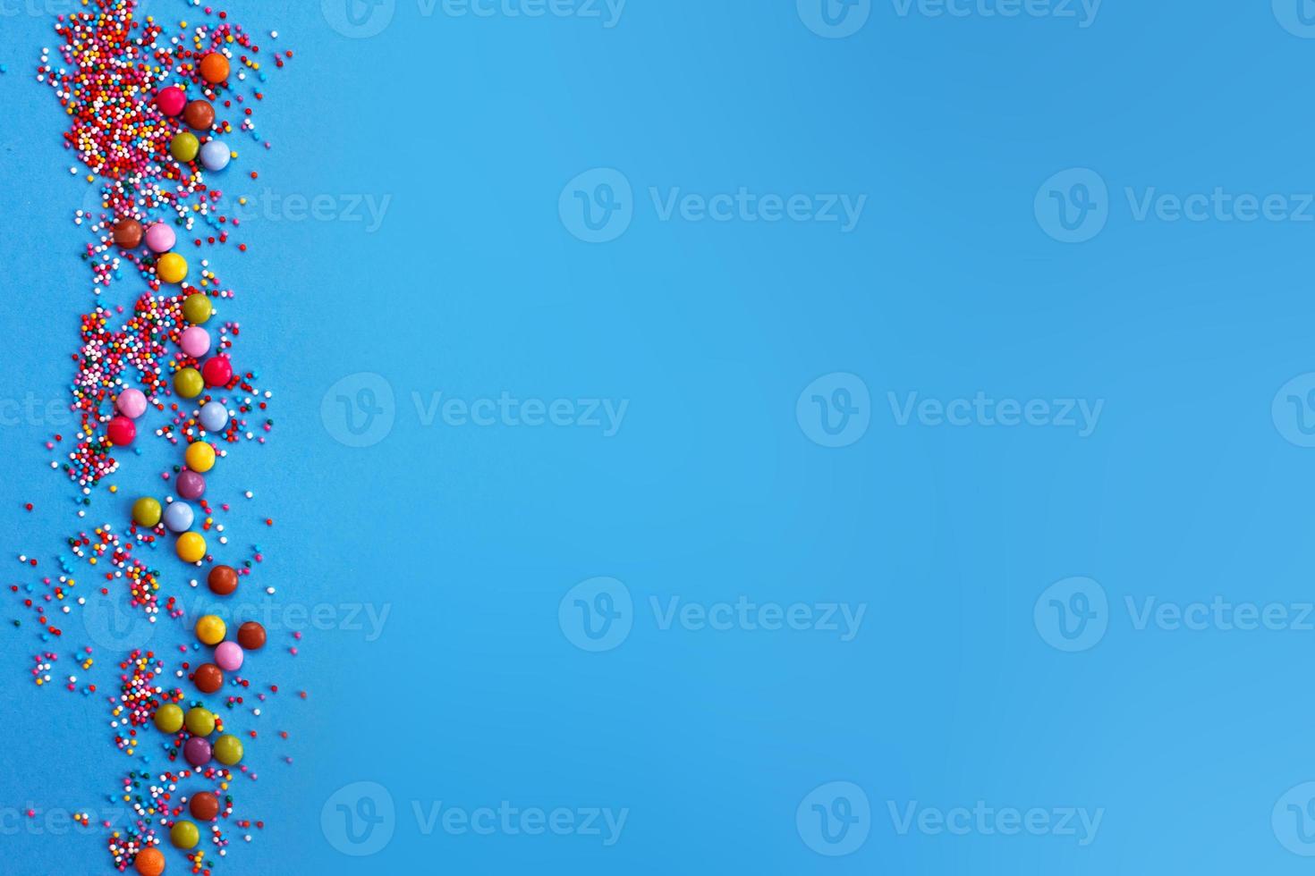 Sugar baking colorful sprinkles in shape of circle isolated on blue background. Holiday concept copy space photo