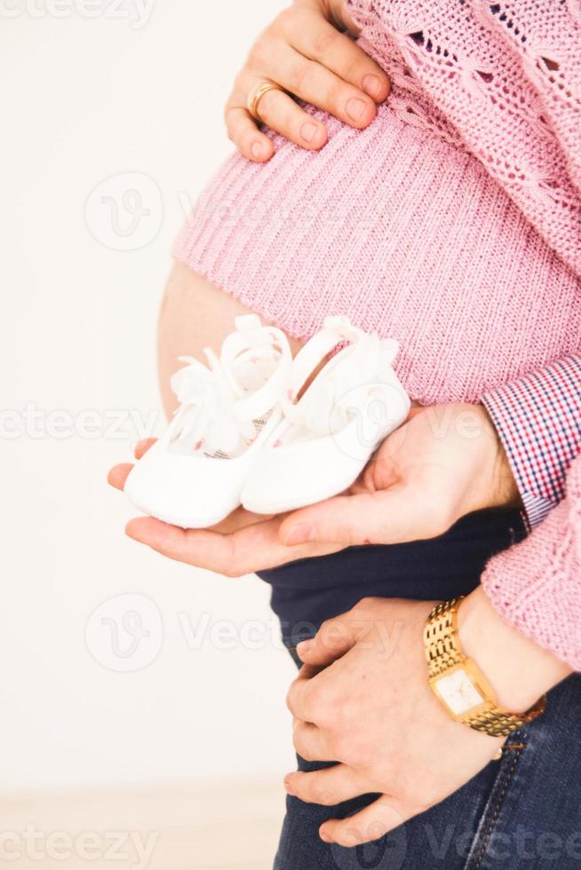 Pregnant woman holding booties from stomach photo