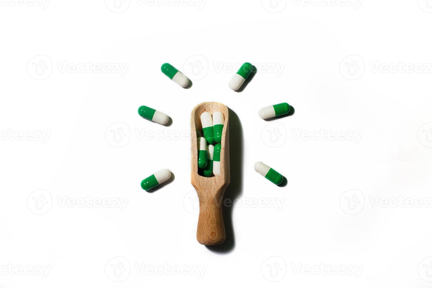 medicine green pills on white background on a wooden spoon in the form of a light bulb . Copy space for text. photo