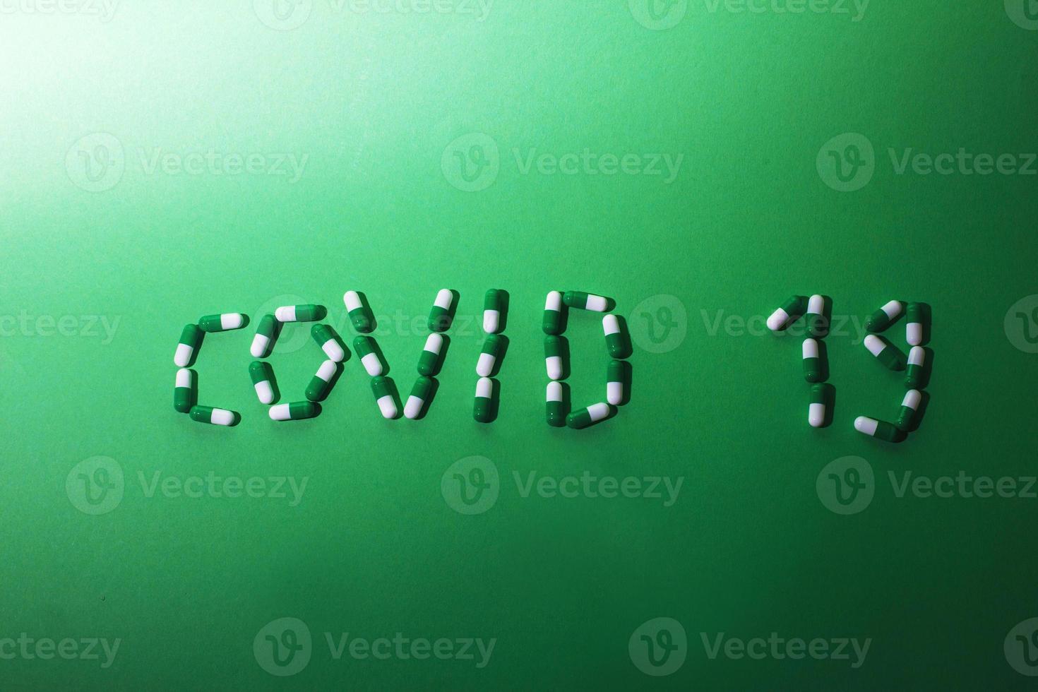 Inscription Covid 19 from letters made of pills on a green background. Corona virus concept. photo