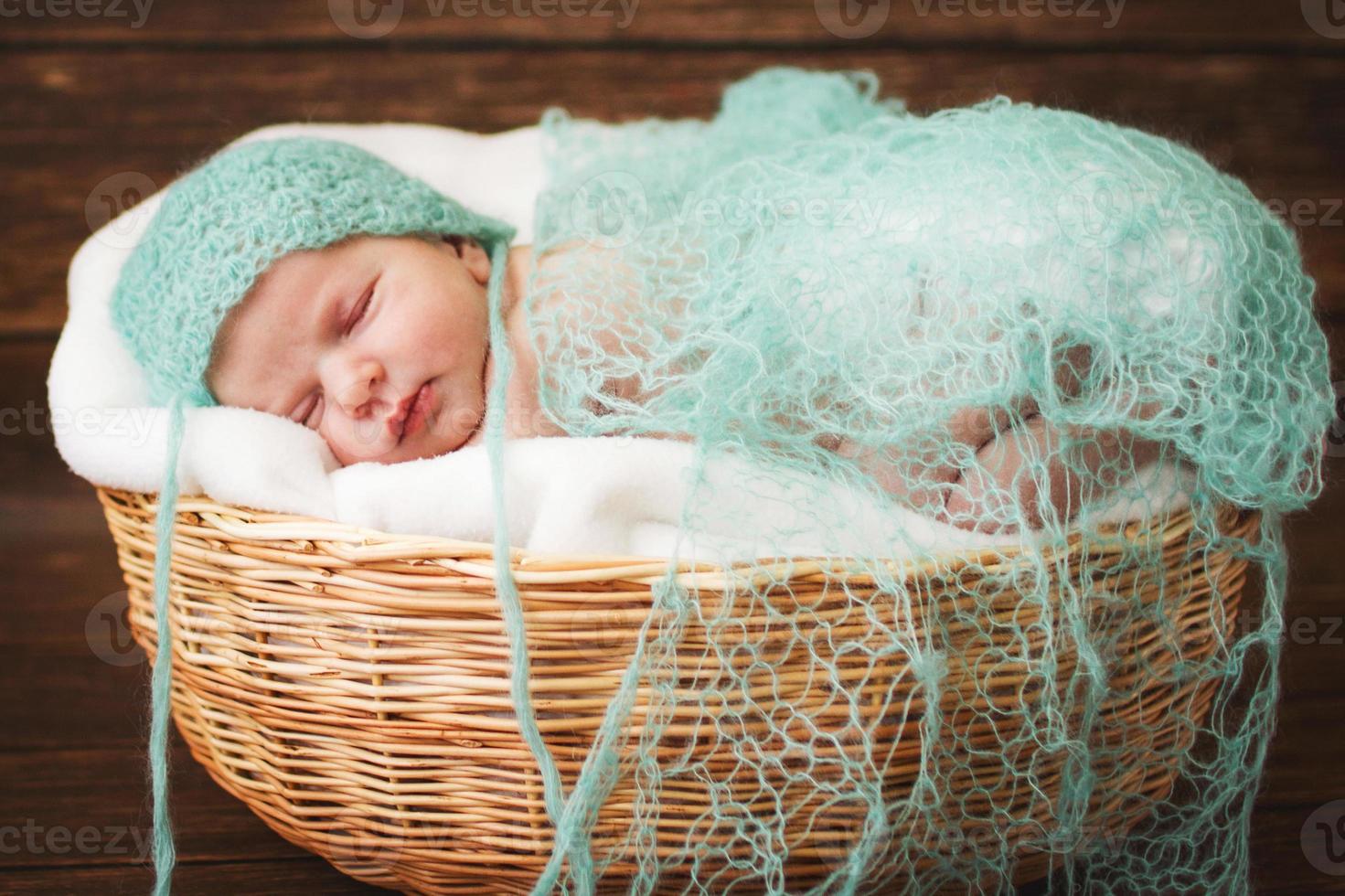 Newborn baby sleeping on a wooden background in the Wicker basket photo