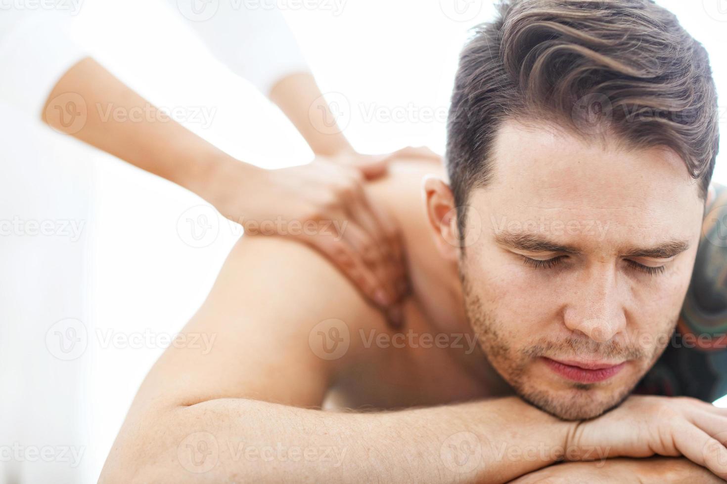 Handsome man having massage in spa salon photo