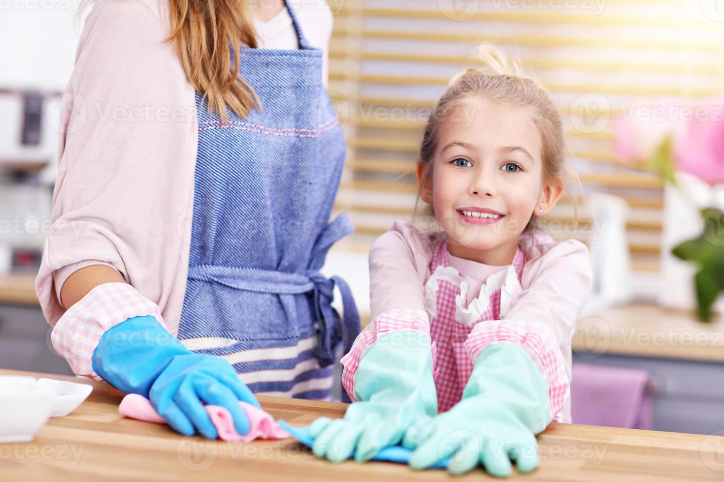 Little girl and her mom in aprons cleaning the kitchen photo