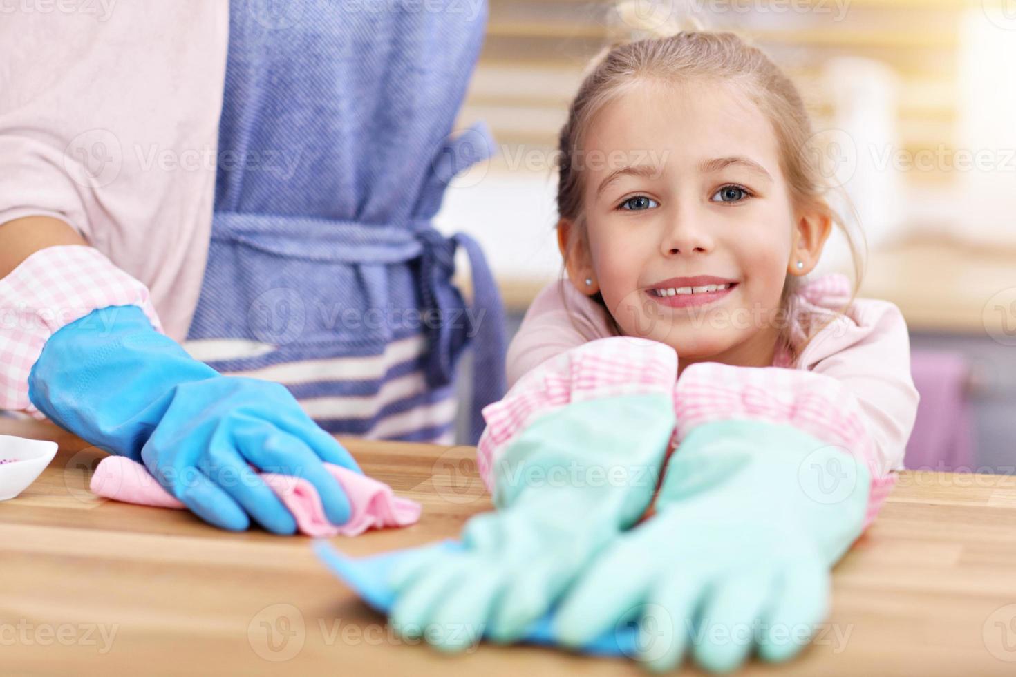 Little girl and her mom in aprons cleaning the kitchen photo