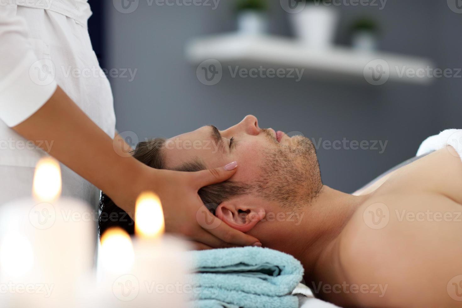 hombre guapo con masaje en el salón de spa foto