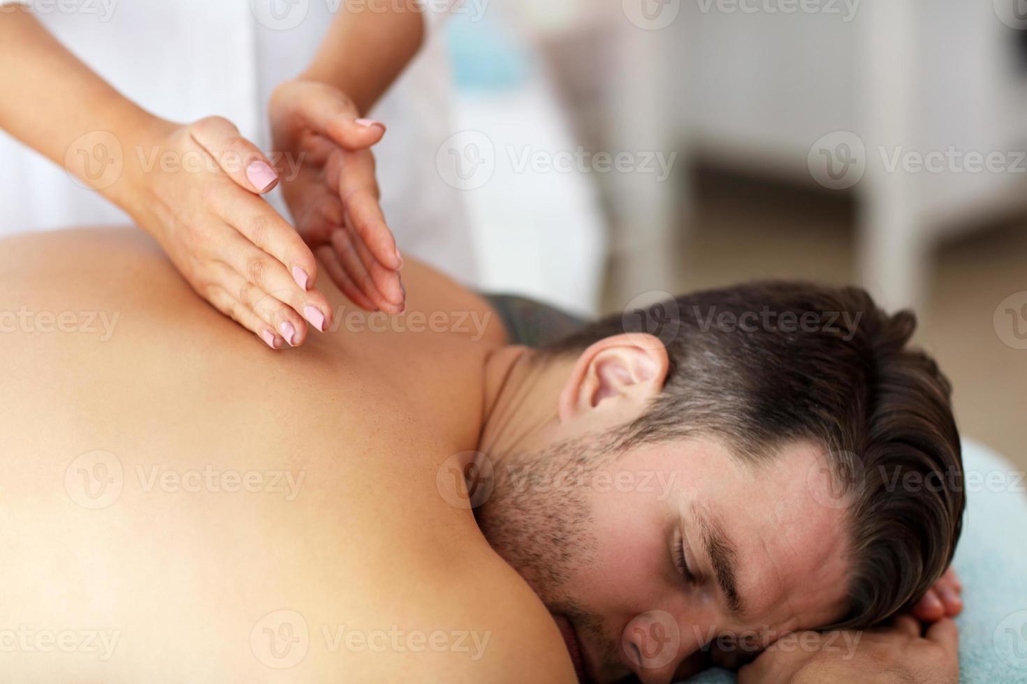 hombre guapo con masaje en el salón de spa foto