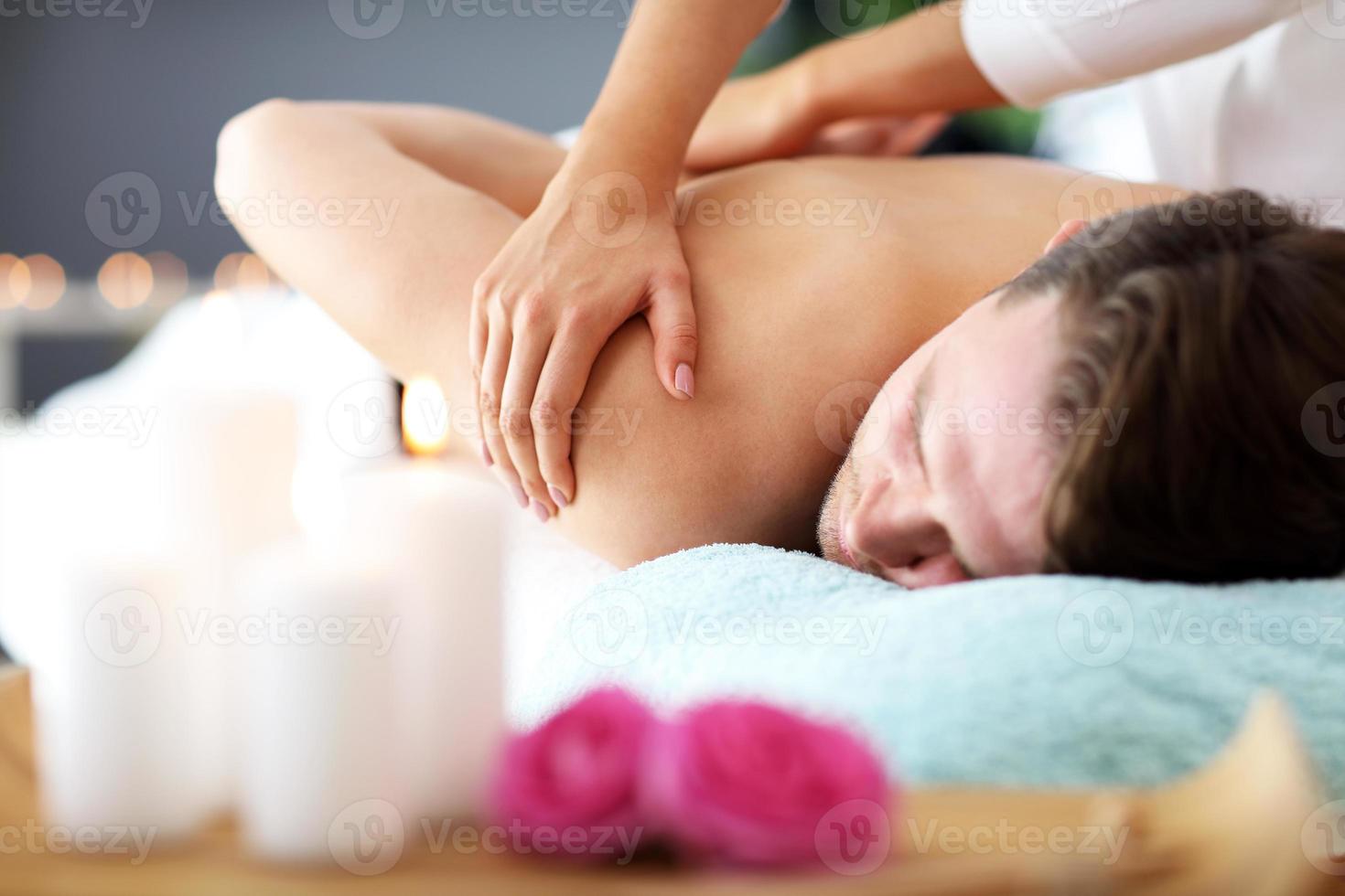 hombre guapo con masaje en el salón de spa foto