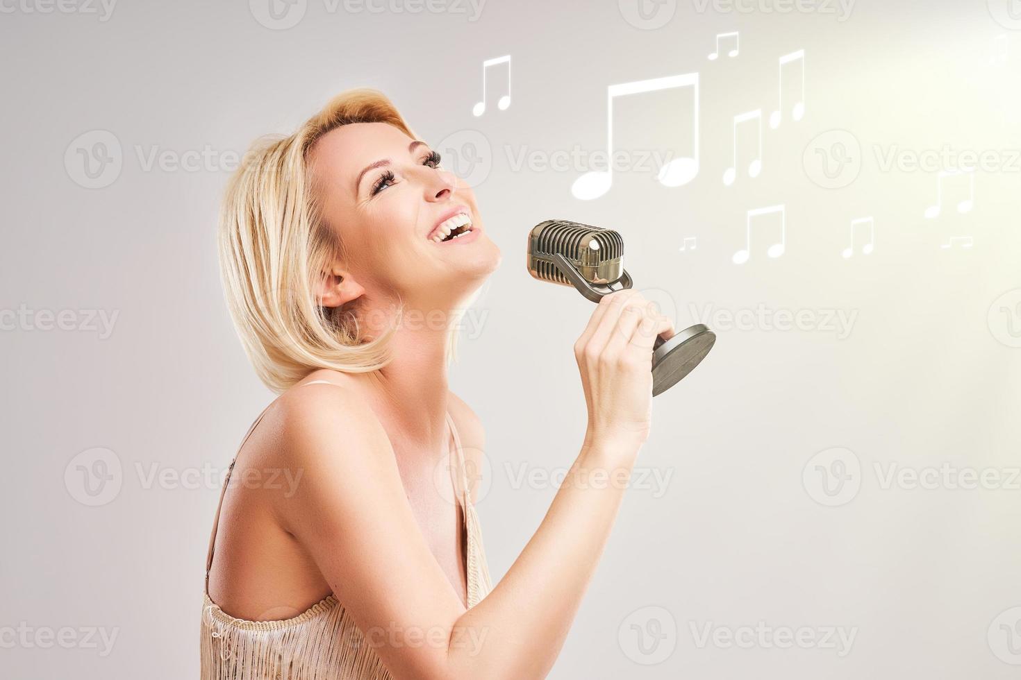 Pretty woman singing over grey background photo