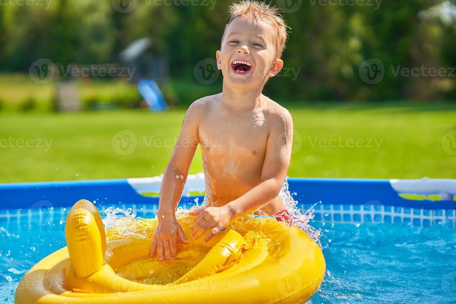 chico lindo nadando y jugando en una piscina en el patio trasero foto