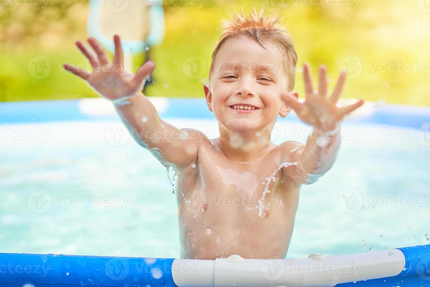 chico lindo nadando y jugando en una piscina en el patio trasero foto