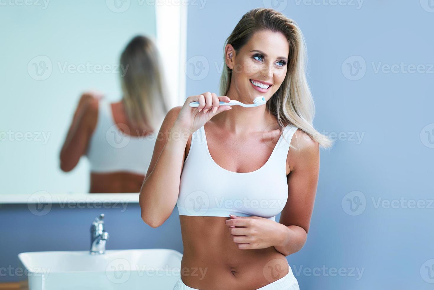 bella mujer cepillándose los dientes en el baño foto