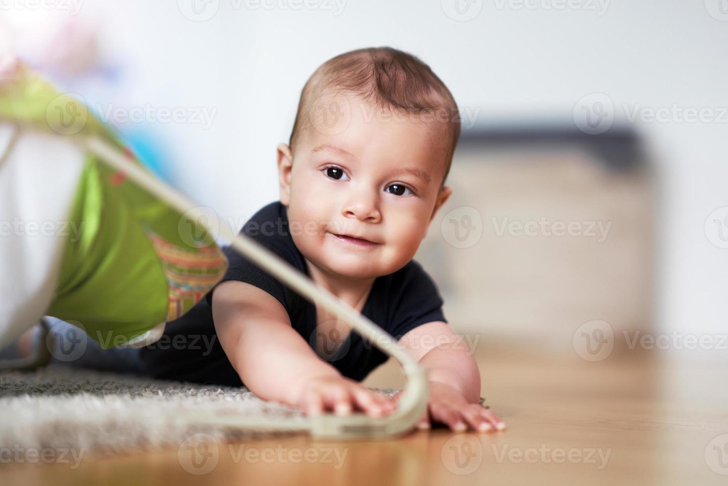 Cute smiling baby boy crawling on floor in living room photo