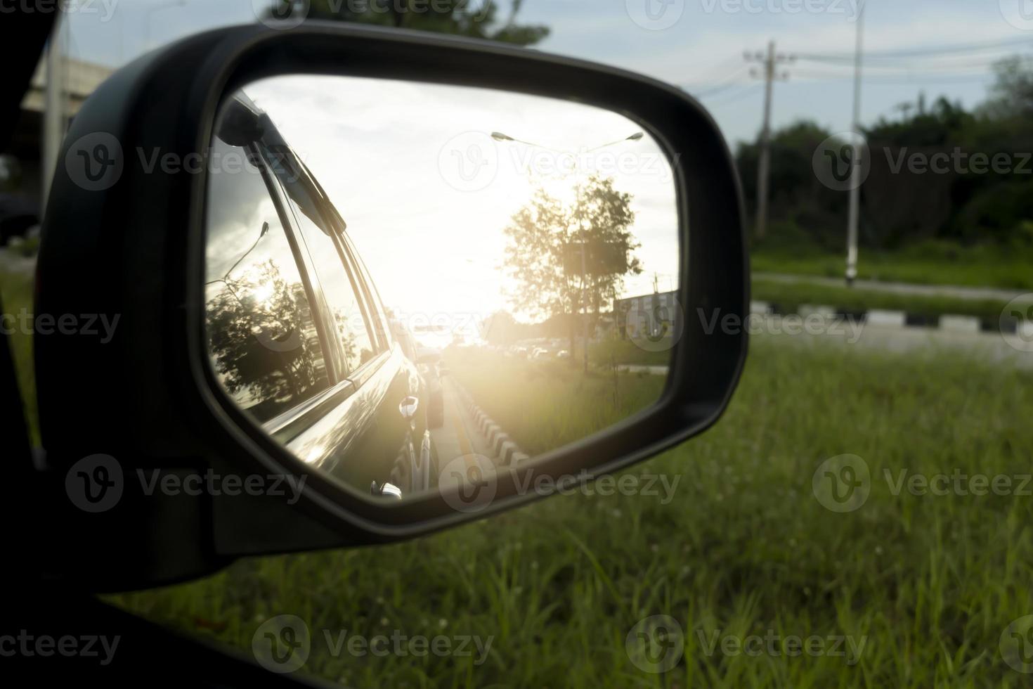 Mirror wing of gray car on the road with many car in traffic jam. In the rush hours and island of green grass. photo