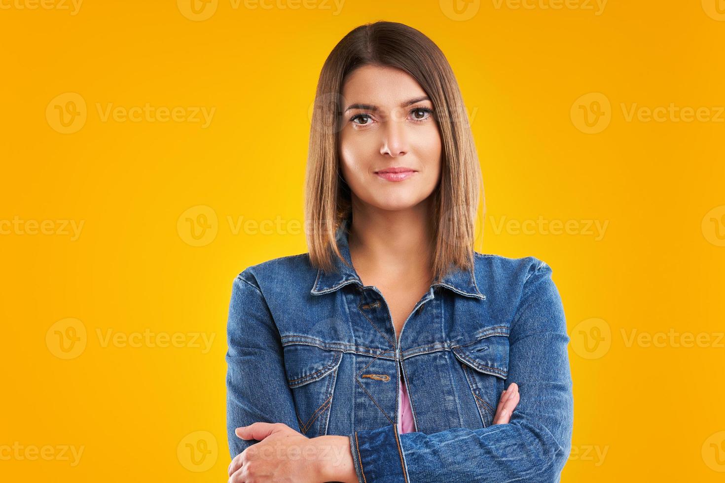 primer plano de una mujer con chaqueta vaquera mirando a la cámara sobre un fondo amarillo foto