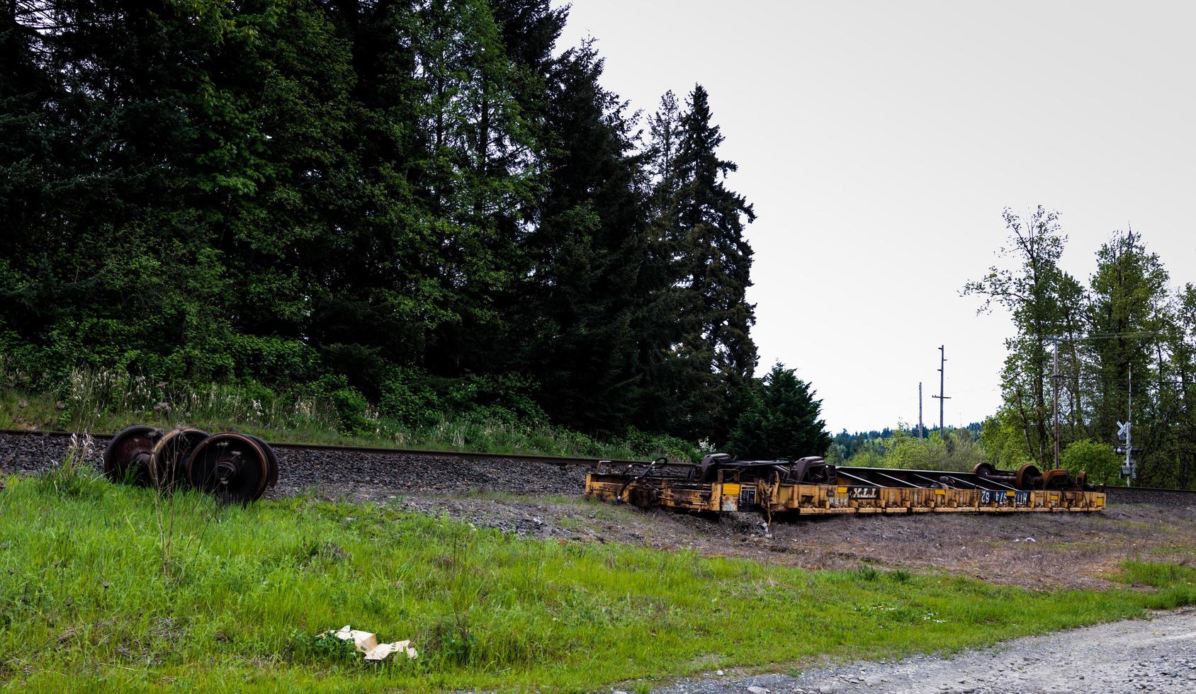 An overturned derailed railroad car lying next to the tracks photo