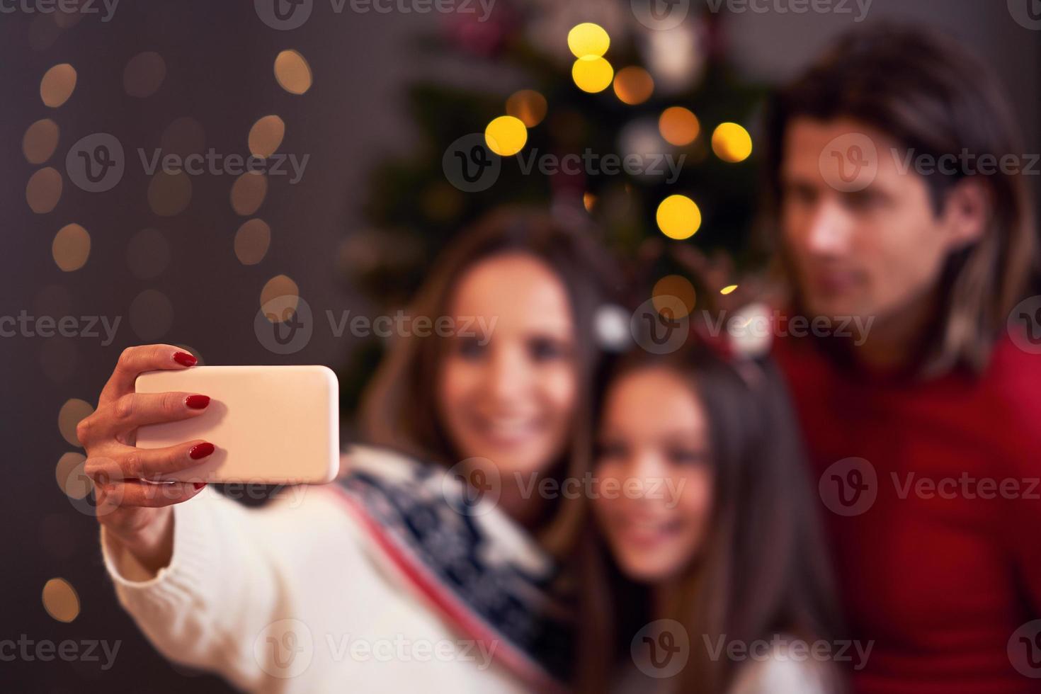 Beautiful family celebrating Christmas at home and taking selfie photo