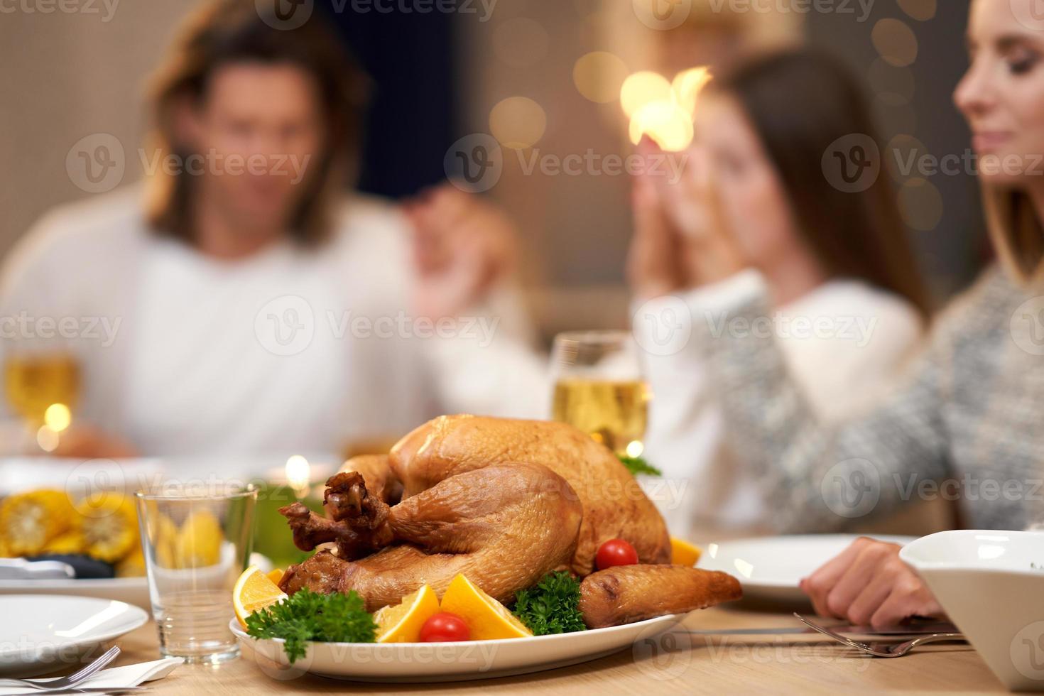 Beautiful family praying over festive dinner at home photo