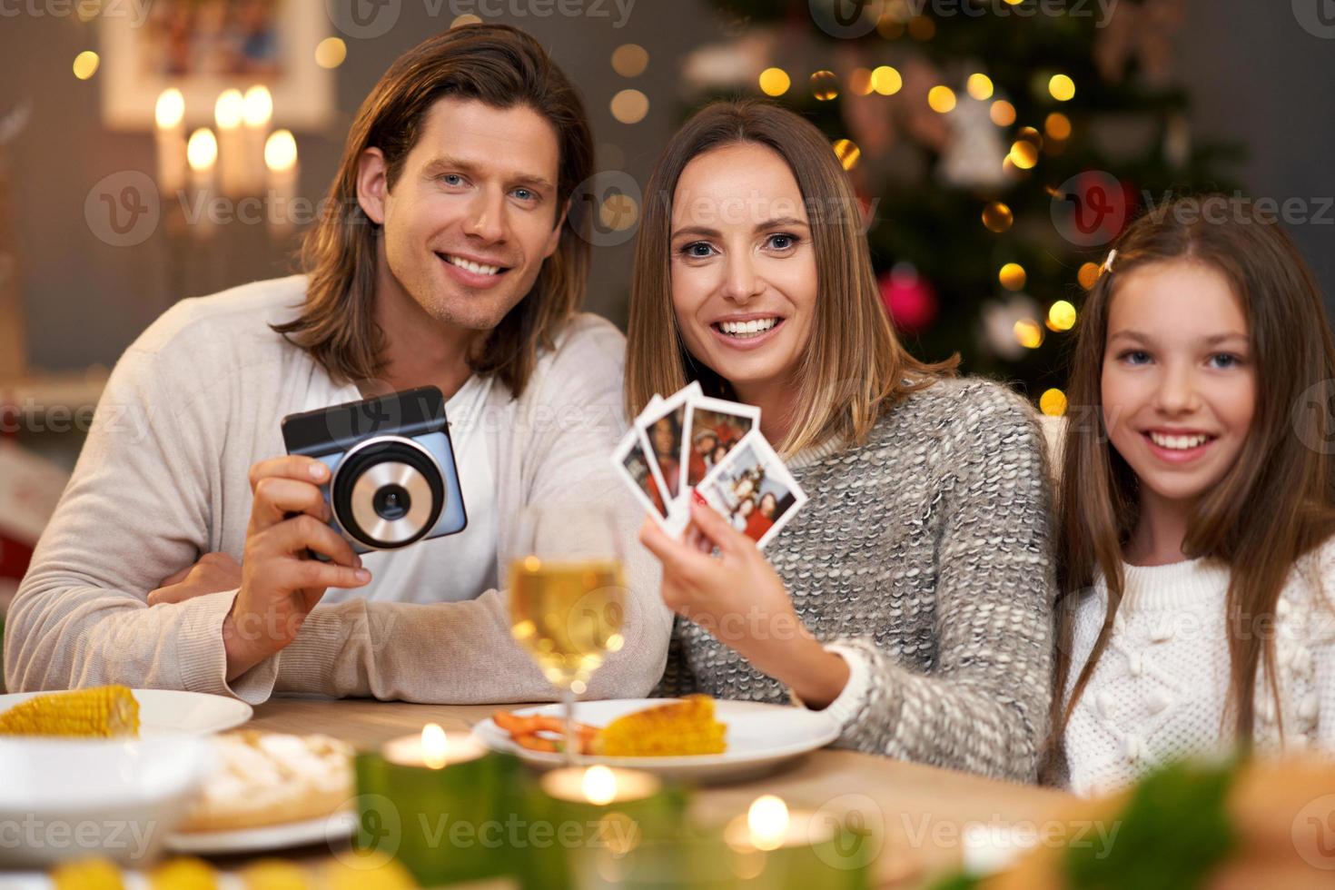 Beautiful family celebrating Christmas at home and taking instant pictures photo