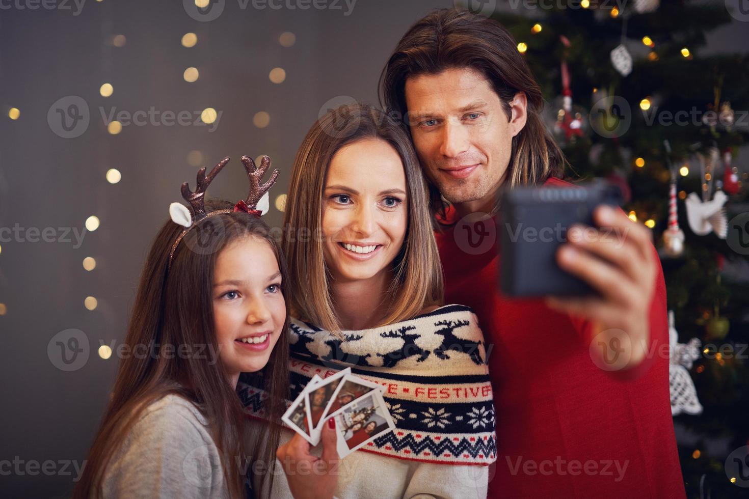 Beautiful family celebrating Christmas at home and taking instant pictures photo