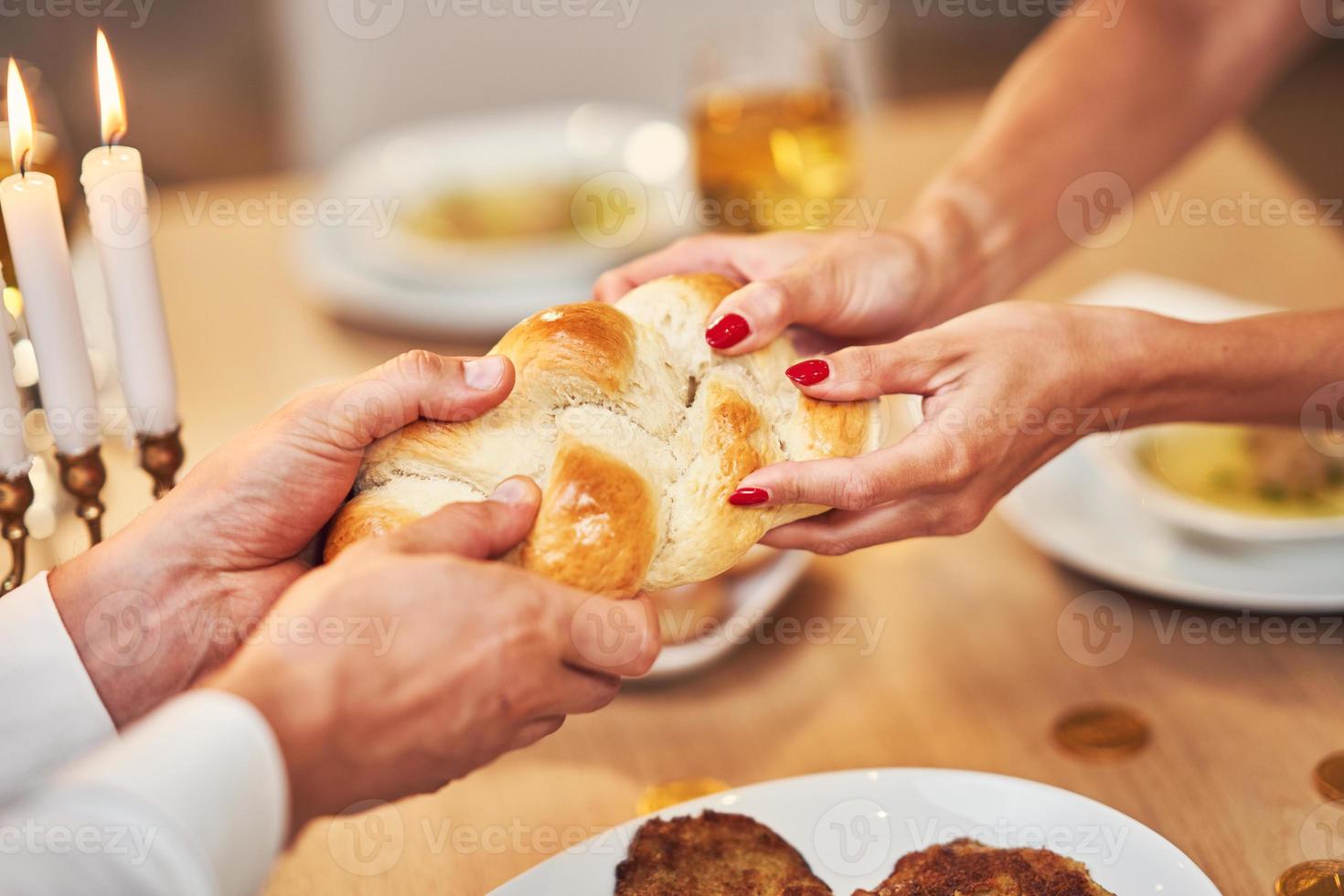 Hanukkah dinner. Family gathered around the table sharing challah photo