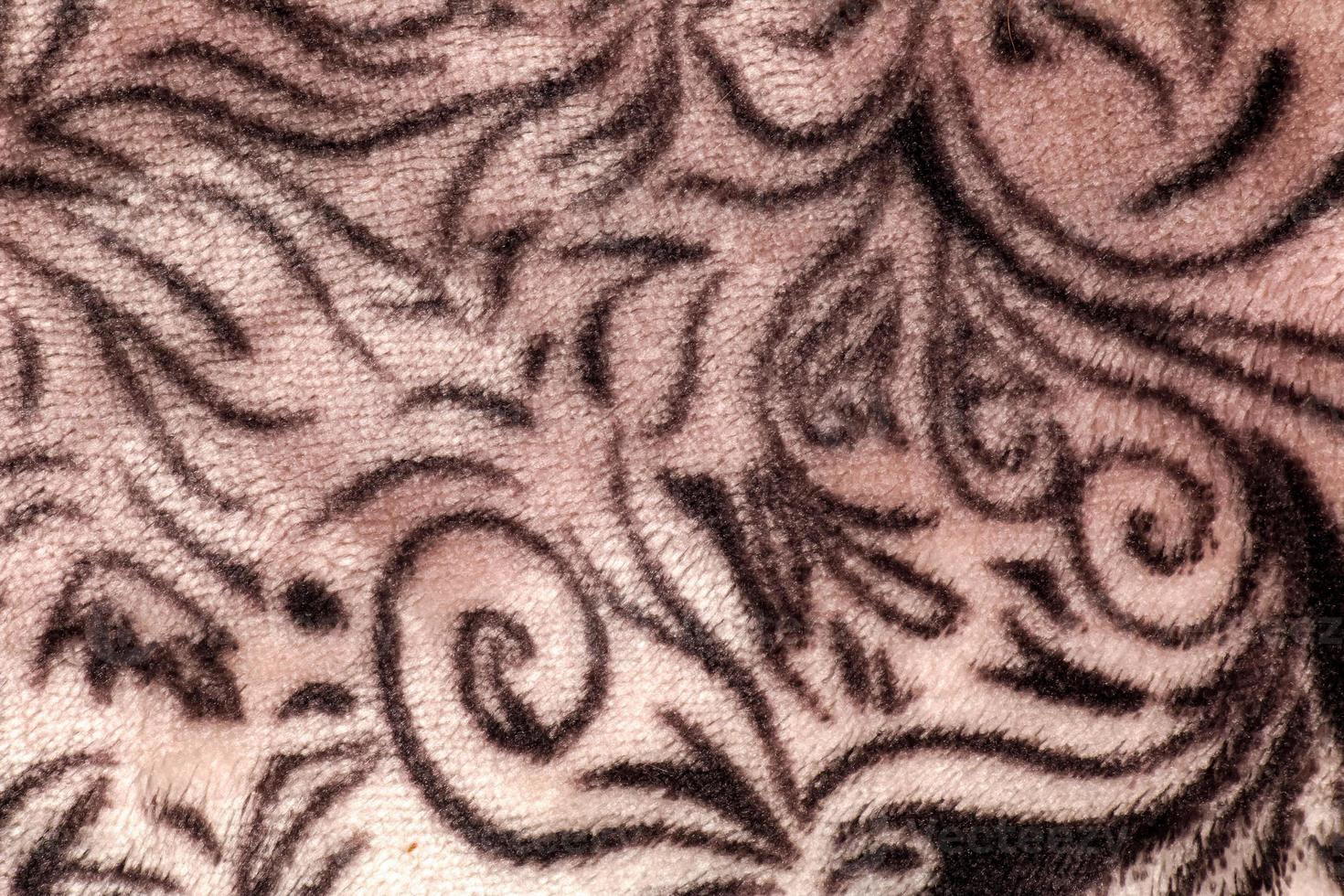 Close-up pattern of fleece fabric with leopard pattern. Brown-beige and black striped repeating on the surface of fur clothes, abstract texture background. photo
