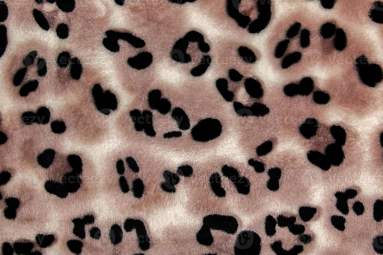 Close-up pattern of fleece fabric with leopard pattern. Brown-beige and black striped repeating on the surface of fur clothes, abstract texture background. photo