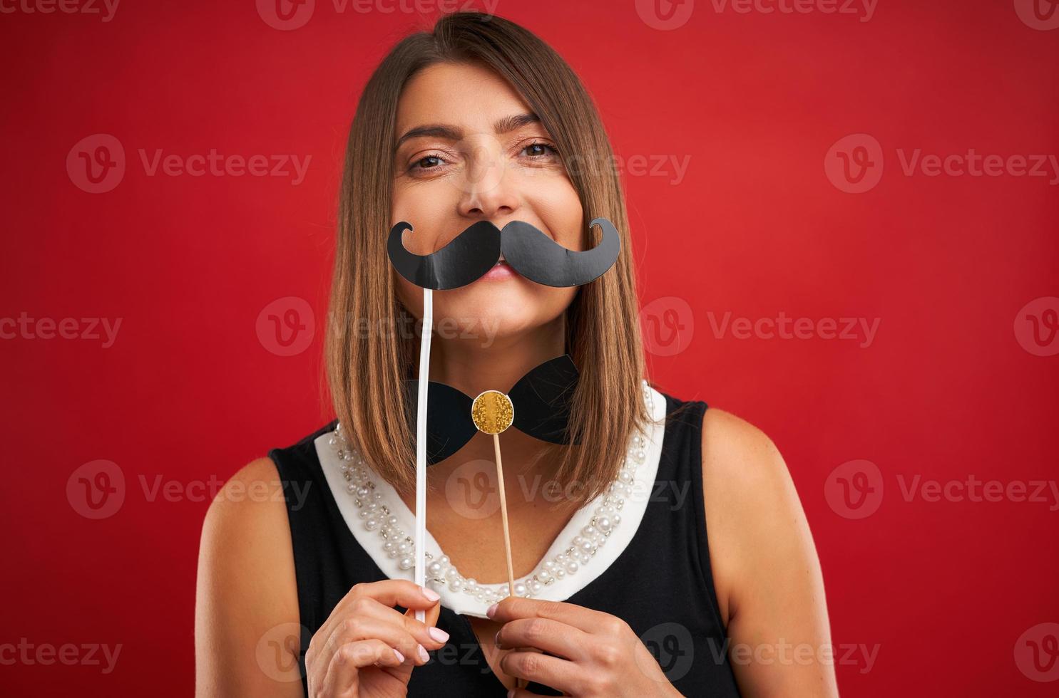 Attractive brunette woman posing with New Year photo gadgets over red background