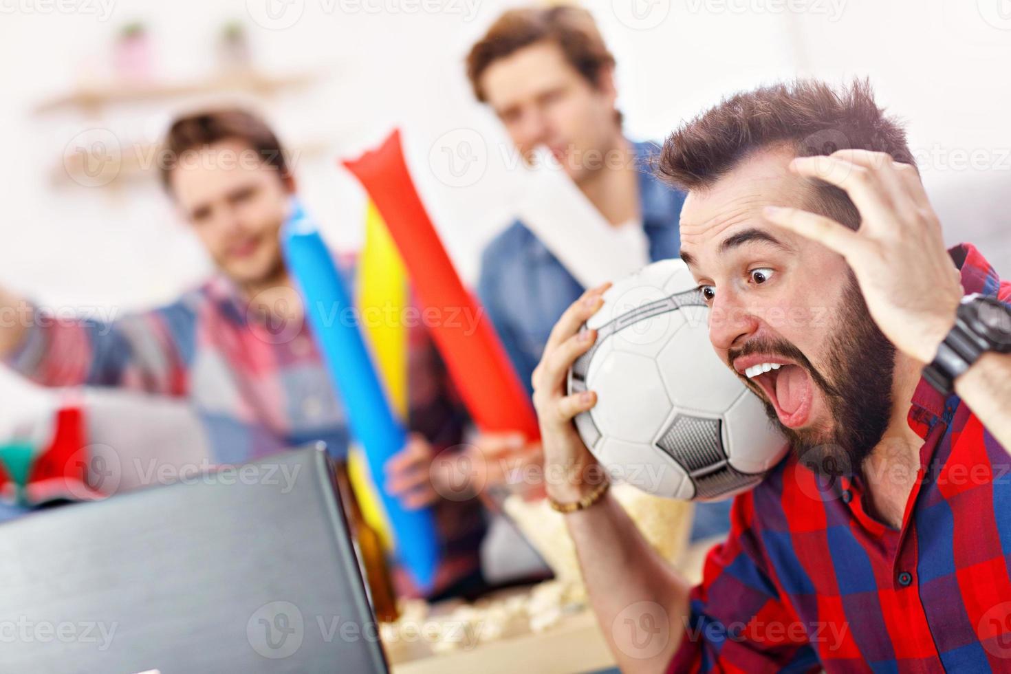 Happy male friends cheering and watching sports on tv photo