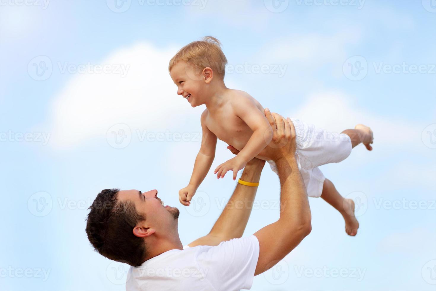 padre divirtiéndose en la playa con su pequeño hijo foto