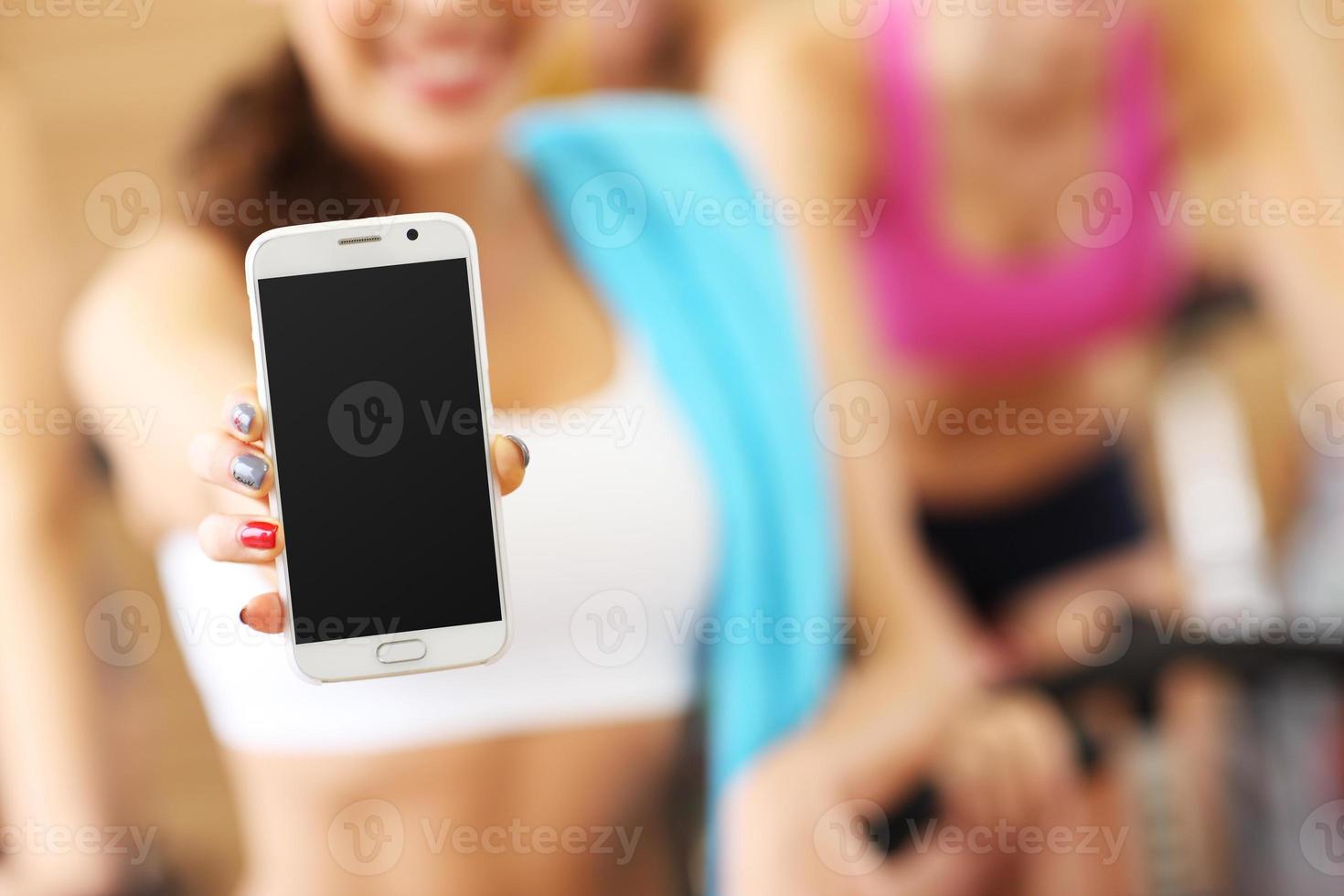 Fit woman holding smartphone in gym photo