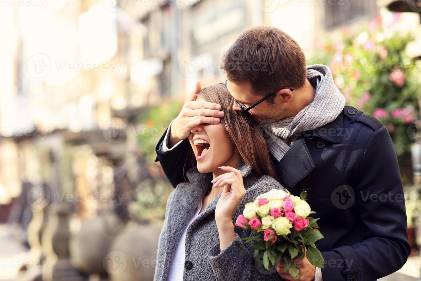 Young man surprising woman with flowers photo