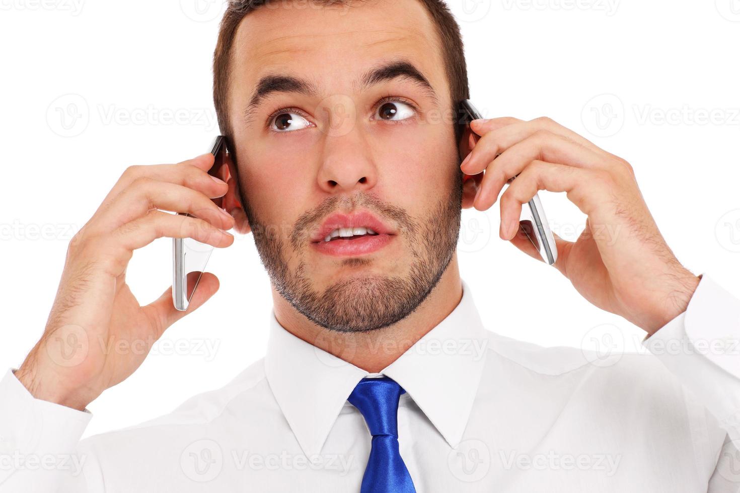 Businessman talking on two phones photo