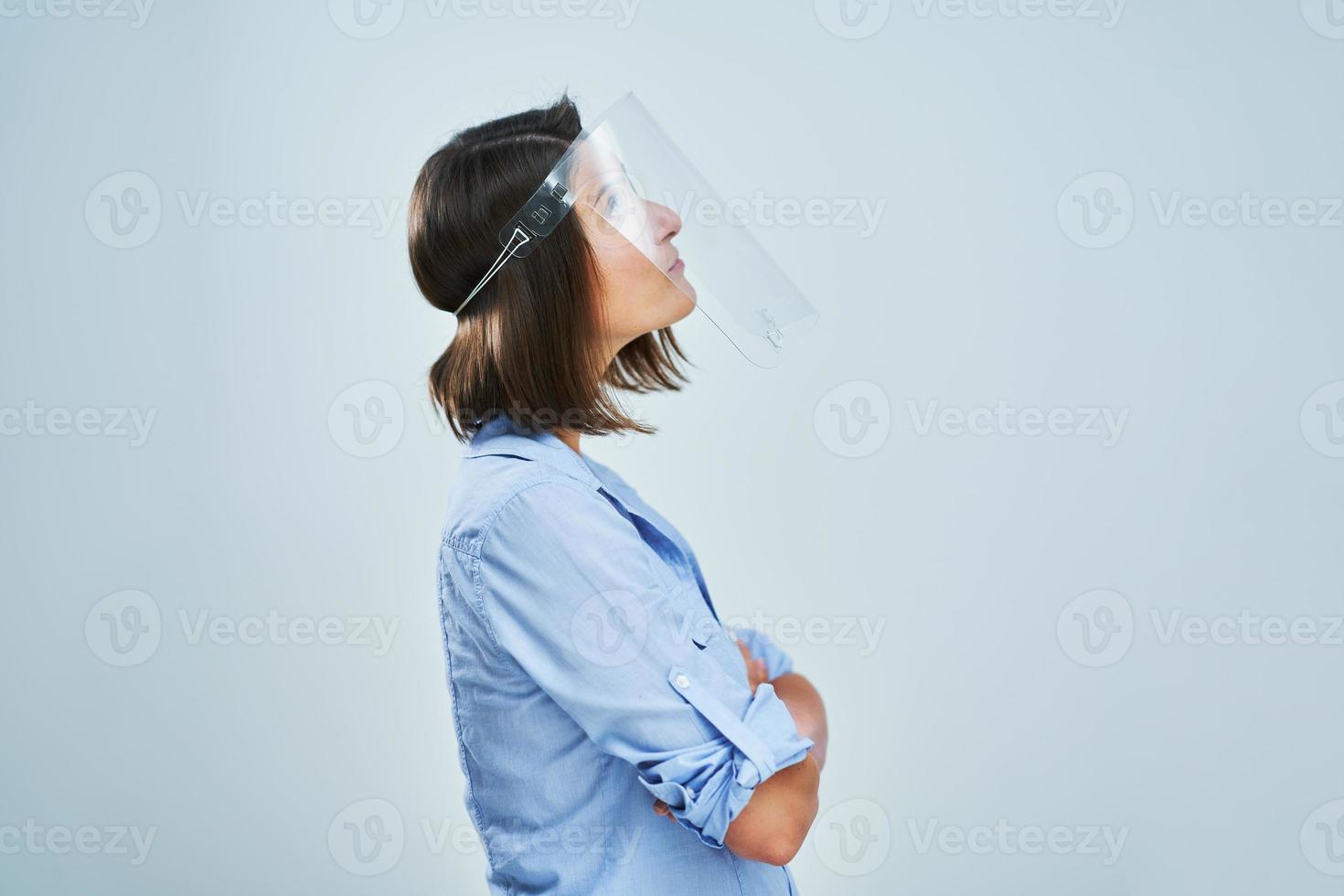 Attractive woman wearing protective shield thinking over white background photo