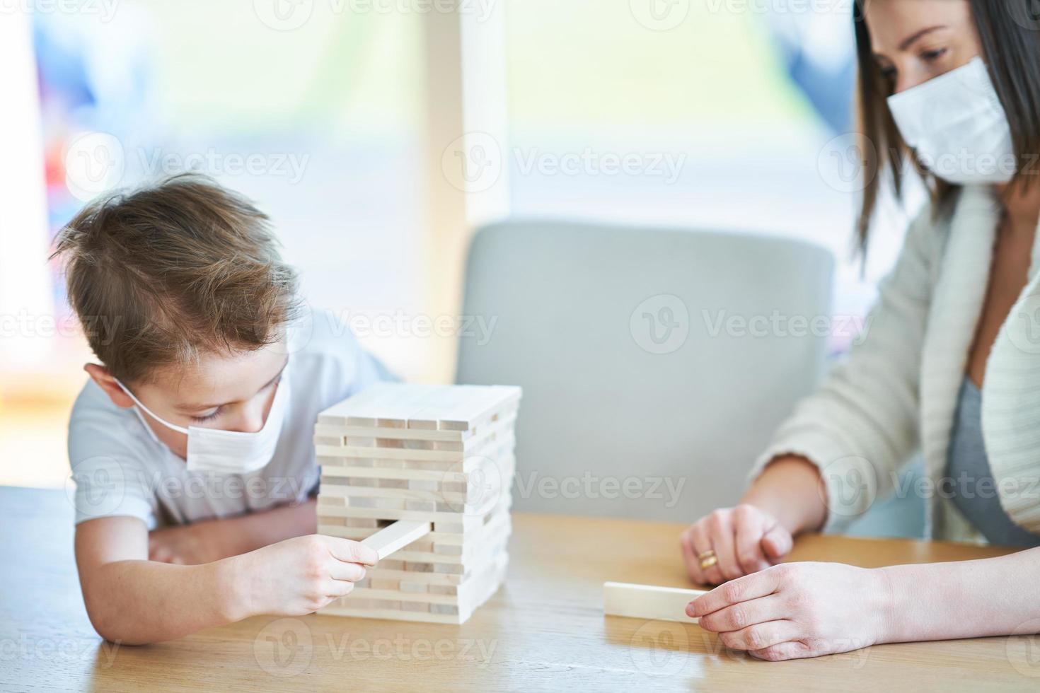 Mother and child playing together at home isolation during coronavirus pandemic photo