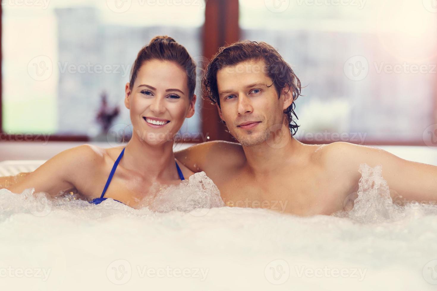 Happy couple enjoying jacuzzi in hotel spa photo