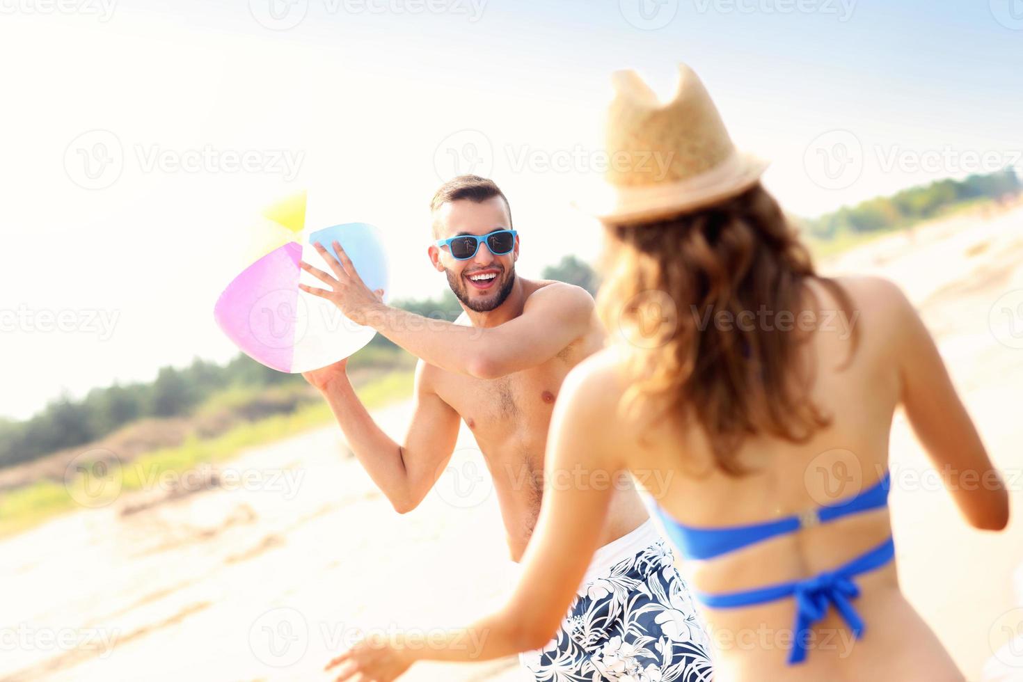 Young couple playing with a ball at the beach photo
