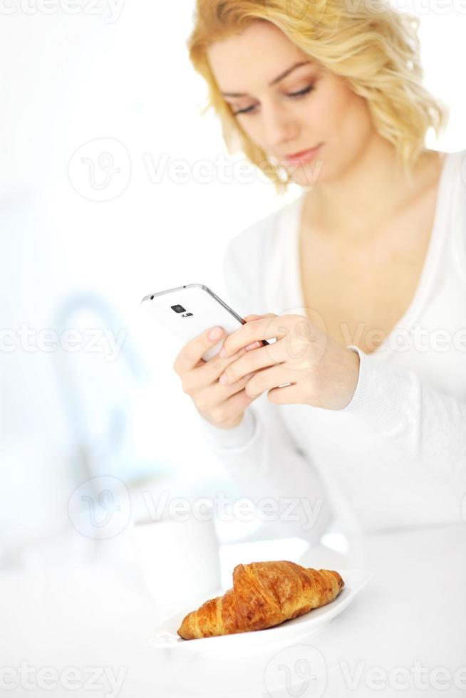 mujer joven con smartphone en la cocina foto