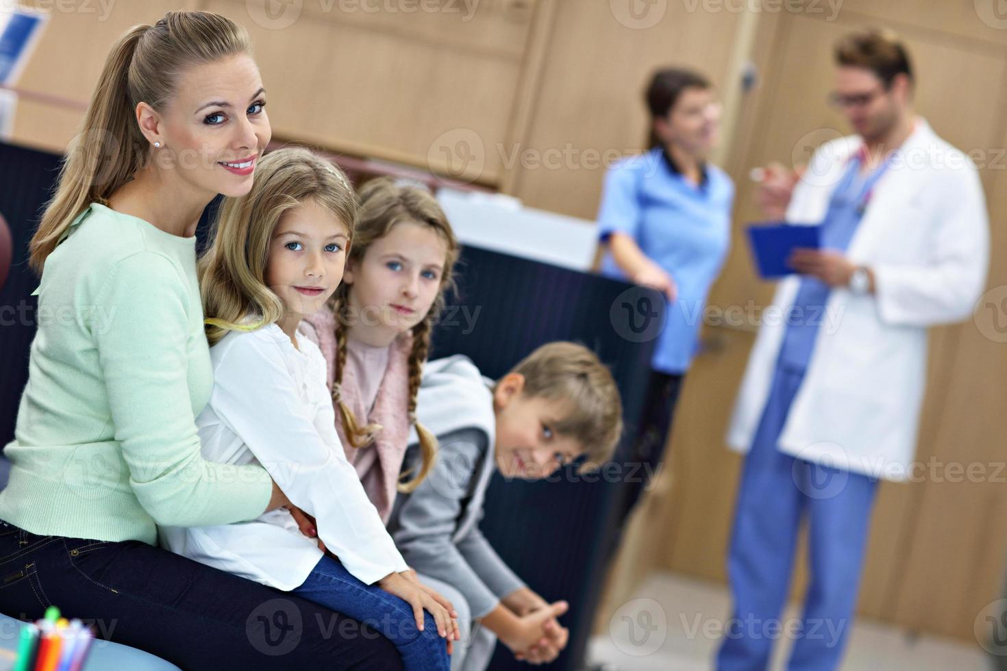 Mother and children waiting in front of registration desk in hospital photo