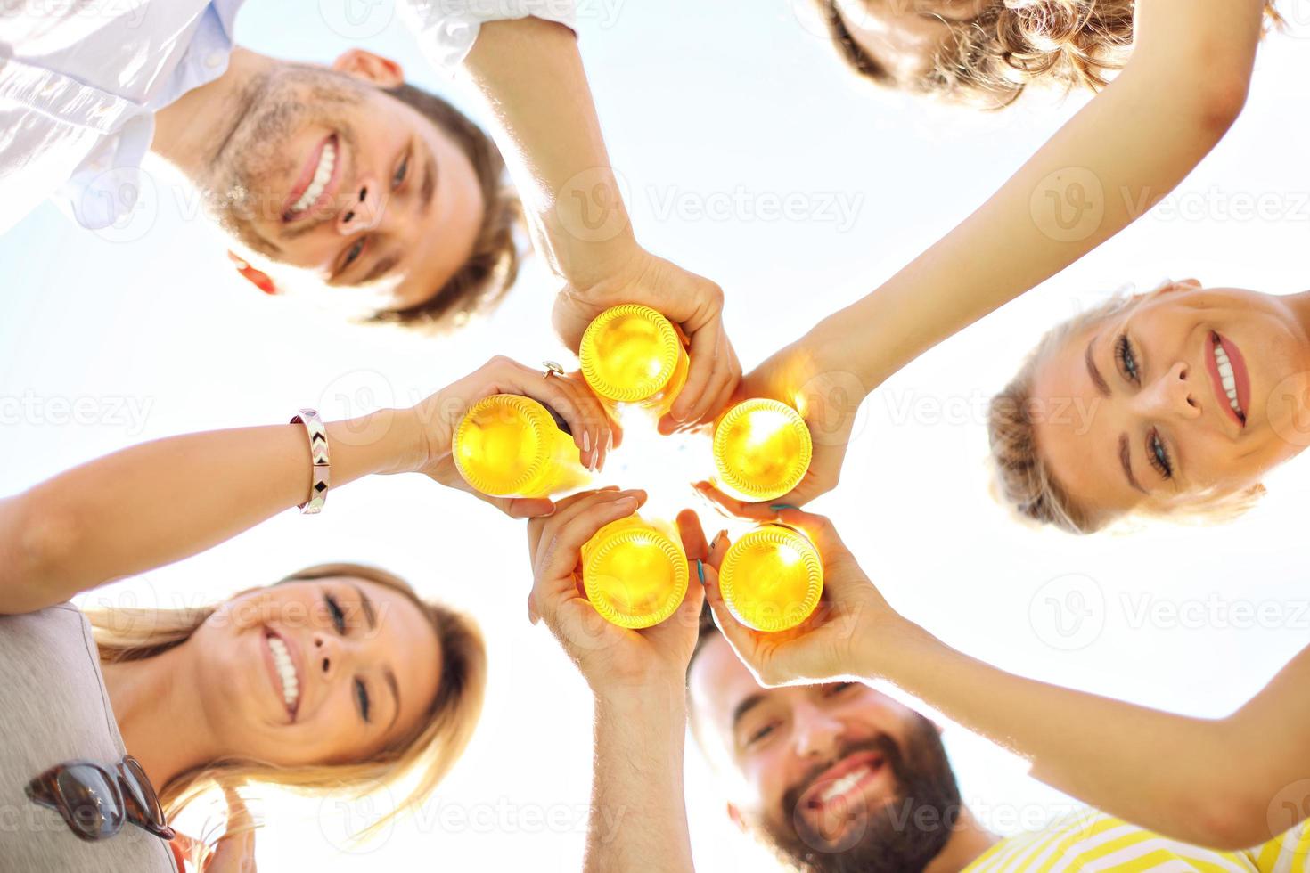 Group of young people cheering and having fun outdoors with drinks photo