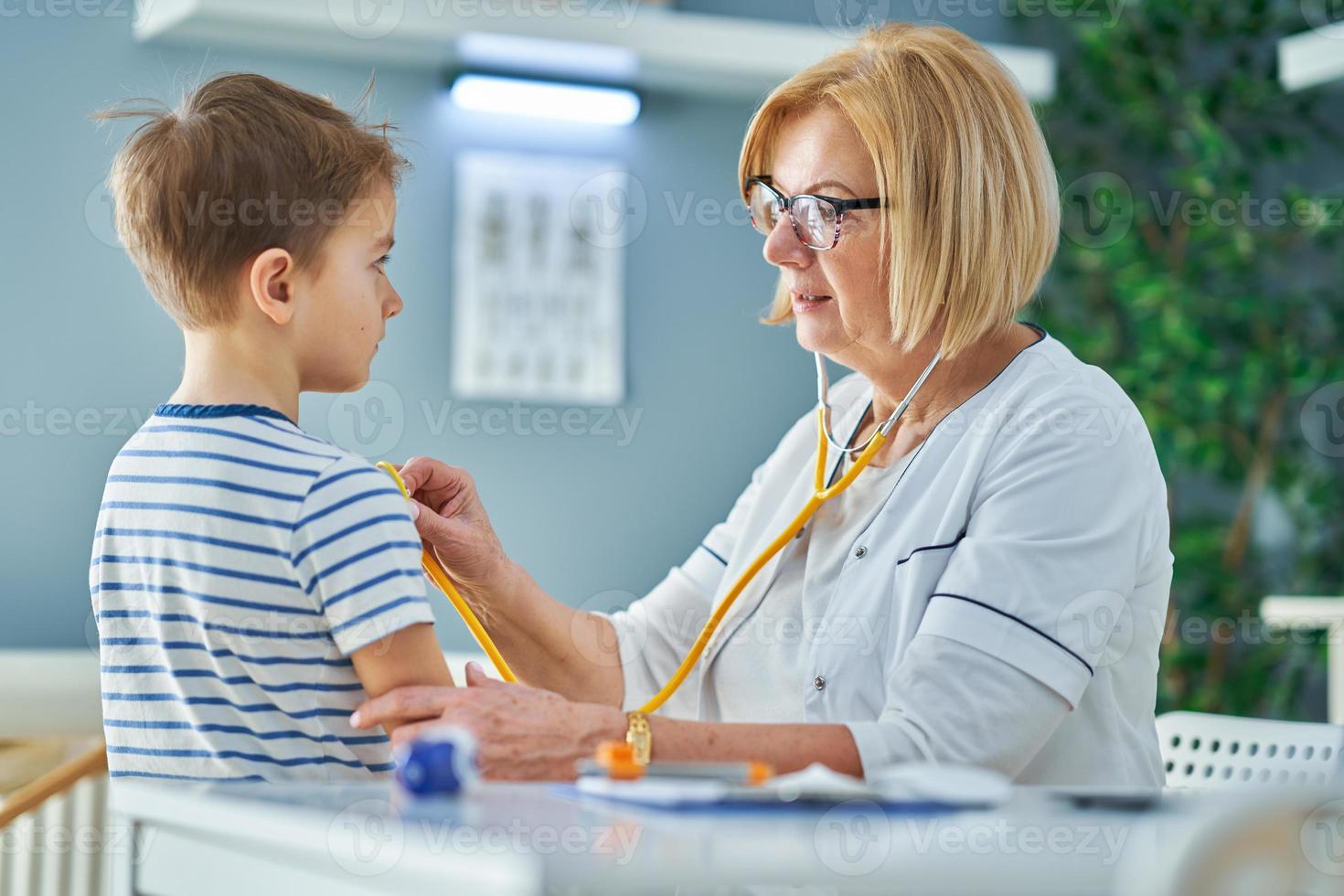 Pediatrician doctor examining little kids in clinic photo